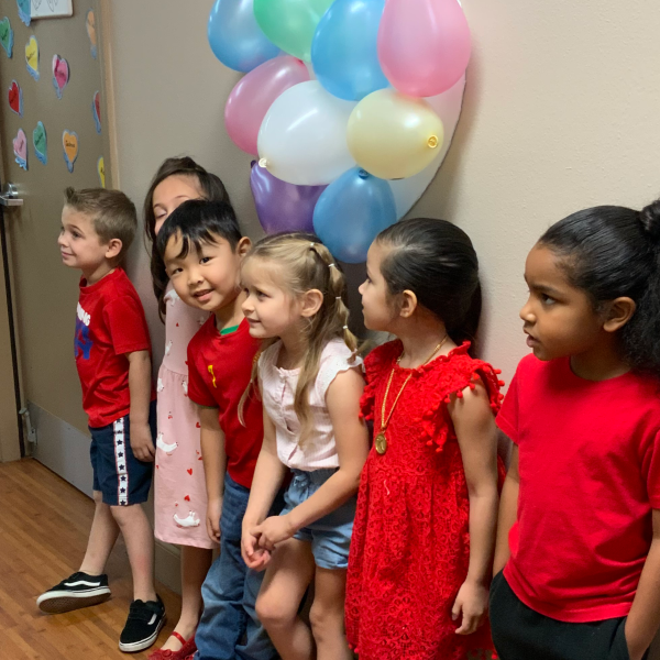 Children dressed in red for Valentine's Day with balloons